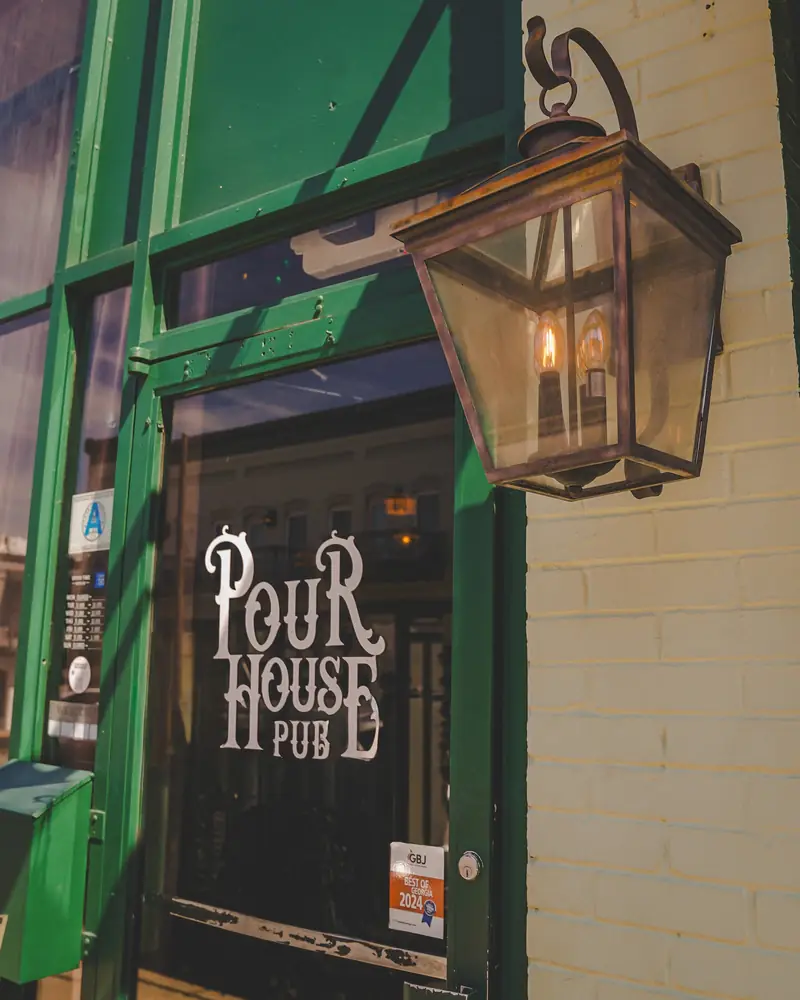The green door at Pour House Pub, with the copper lantern beside it