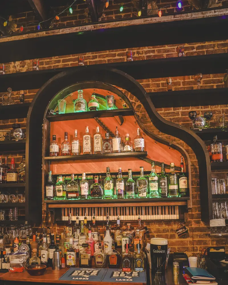 The piano-shaped back bar with its bottles lit green and a Guinness at the end